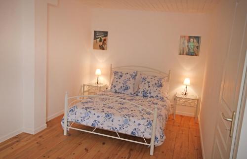 1 dormitorio con 1 cama blanca con colcha de flores y 2 lámparas en Cottage at 7 en Sainte-Foy-la-Grande