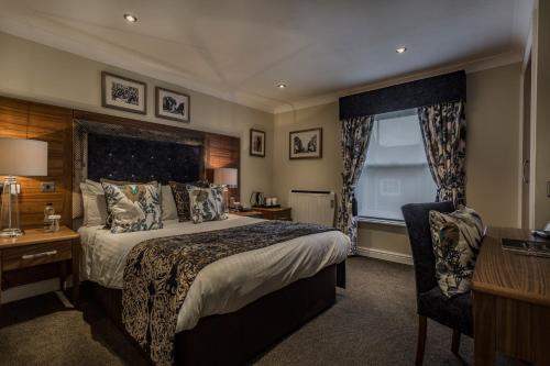 a bedroom with a bed and a desk and a chair at The Admiral Rodney Hotel, Horncastle, Lincolnshire - The Coaching Inn Group in Horncastle