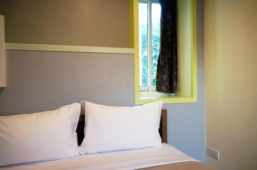 a bed with two white pillows and a window at Samsen Sam Place in Bangkok
