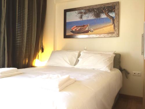 Elvita Athens Sea View Maisonette في أثينا: غرفة نوم بسرير ابيض مع لوحة على الحائط