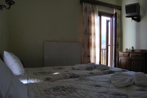 a bedroom with a bed and a window and a television at Rizoma Guesthouse in Mikrón Khoríon