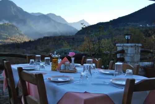 a table with plates and glasses on top of a mountain at Rizoma Guesthouse in Mikrón Khoríon