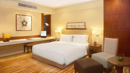 a bedroom with a large white bed and a desk at New Coast Hotel Manila in Manila