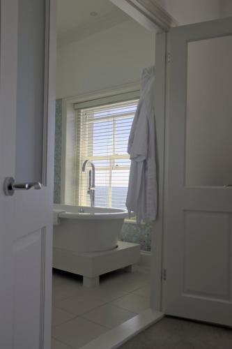 a white bathroom with a tub and a window at The Hambrough in Ventnor
