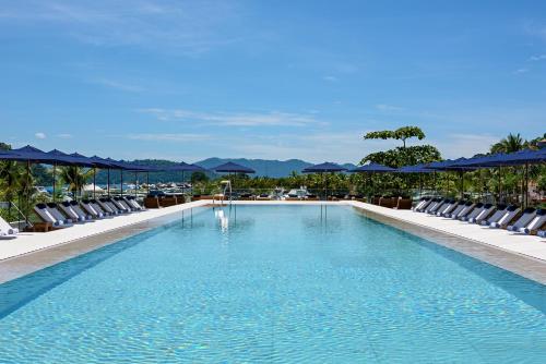duży basen z leżakami i niebieskimi parasolami w obiekcie Hotel Fasano Angra dos Reis w mieście Angra dos Reis