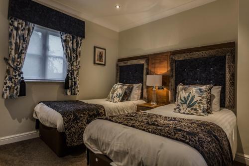 a hotel room with two beds and a window at The Admiral Rodney Hotel, Horncastle, Lincolnshire - The Coaching Inn Group in Horncastle