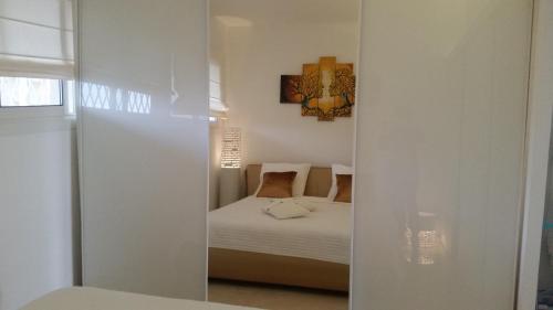 Cette chambre blanche comprend un lit et un miroir. dans l'établissement Appartement Le Chantilly, à Cagnes-sur-Mer