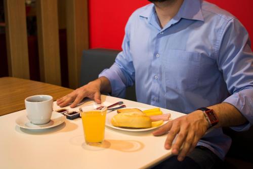 a man sitting at a table with a plate of food at ibis Aracruz in Aracruz