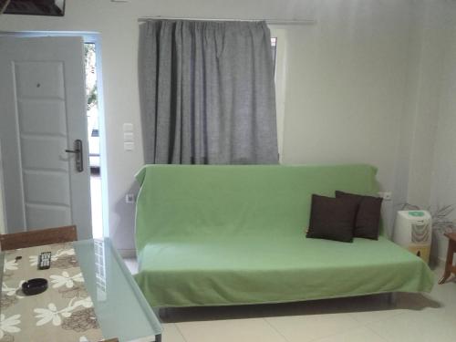 un sofá verde en una sala de estar con ventana en Errica Apartment en Preveza