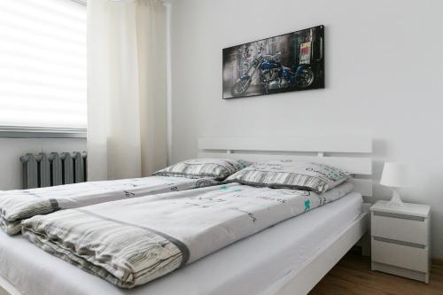 a white bedroom with a bed with a picture on the wall at Zielona Herbowa in Lublin