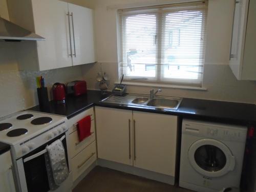 a kitchen with a sink and a washing machine at Clydebank Apartment in Glasgow