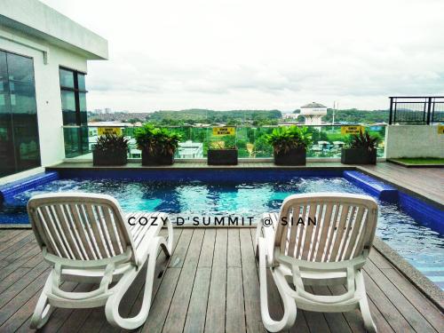 two chairs sitting on a deck next to a swimming pool at COZY D'Summit 2 Bedrooms @ 100mbps HIGH SPEED WIFI in Skudai
