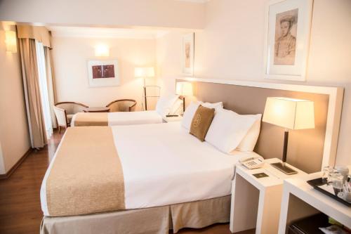 a hotel room with two beds and a desk at Huentala Hotel in Mendoza