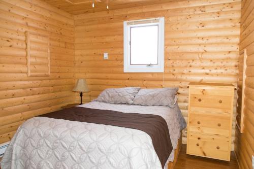 1 dormitorio con 1 cama en una cabaña de madera en Burnt Cape Cabins, en Raleigh