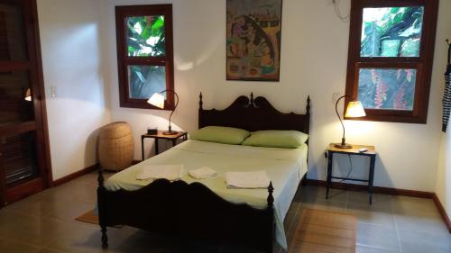 um quarto com uma cama com duas mesas e duas janelas em Bangalôs Parque Verde em Paraty