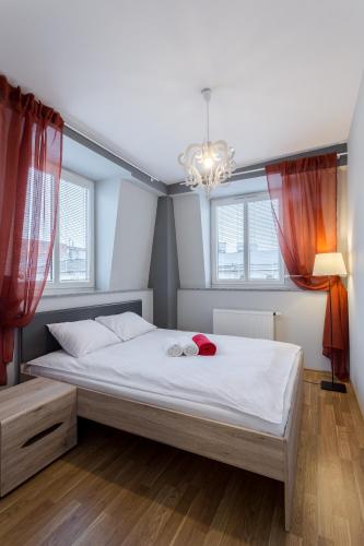 a bedroom with a large white bed with red curtains at Apartamenty Centrum Częstochowa Stara Kamienica in Częstochowa