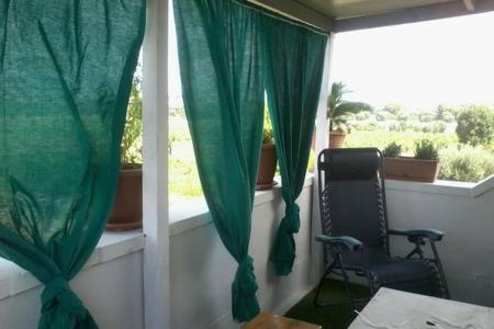 マルッジョにあるIl rifugio dell'Artistaの緑のカーテンと椅子が備わる窓付きの客室です。