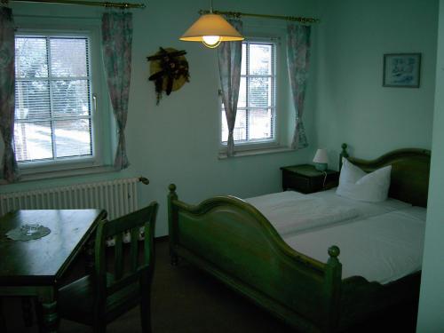 a bedroom with a bed and a table and two windows at Landhotel am Fuchsbach in Berga