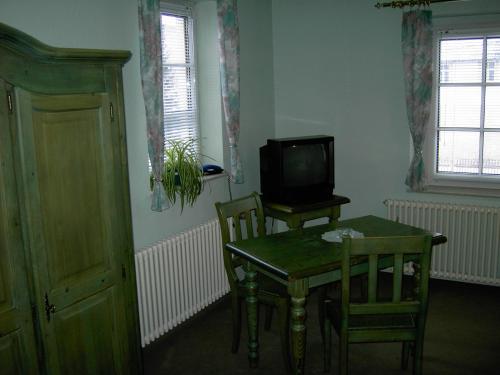 a dining room with a table and a television at Landhotel am Fuchsbach in Berga