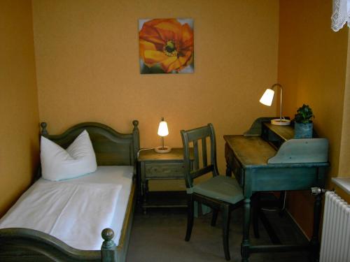 a bedroom with a bed and a desk and a chair at Landhotel am Fuchsbach in Berga