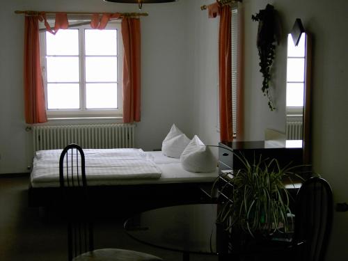 a bedroom with a bed and a table and two windows at Landhotel am Fuchsbach in Berga