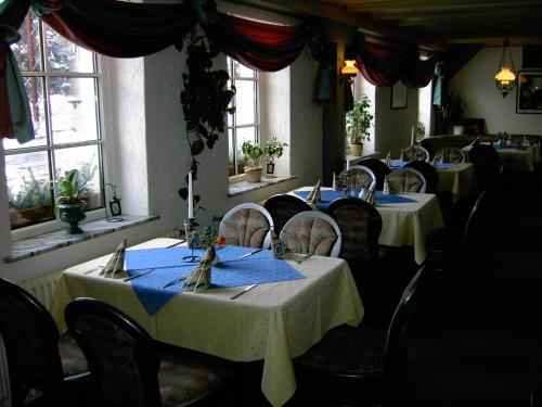 a dining room with tables and chairs with blue napkins at Landhotel am Fuchsbach in Berga