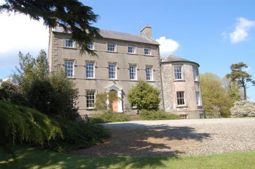 an old stone house with a tree in front of it at Ballydugan Country House in Downpatrick