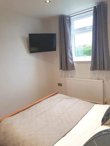 a bedroom with a bed with a flat screen tv on the wall at The Studio in Ingoldmells