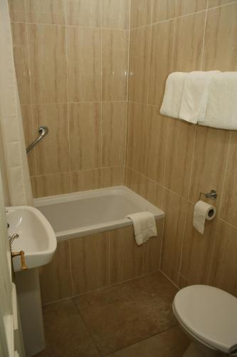 a bathroom with a tub and a toilet and a sink at Woodhill House in Ardara
