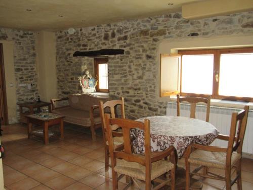 Habitación con mesa, sillas y pared de piedra. en Hotel rural Valtarranz en Noceco