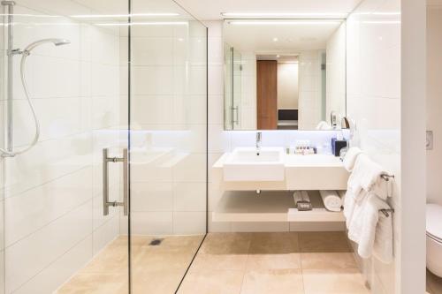 a white bathroom with a sink and a shower at Commodore Airport Hotel Christchurch in Christchurch