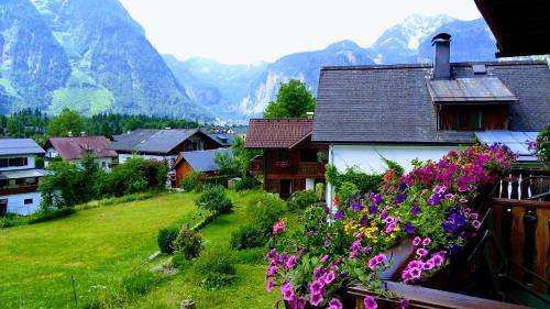 a village with mountains in the background with flowers at Haus Hepi in Obertraun