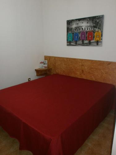 un tavolo rosso in una stanza con un dipinto sul muro di Appartamenti SottoSopra a Porto Cesareo