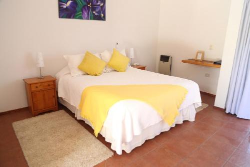 a bedroom with a large bed with yellow pillows at Hotel Altos de Tuqui in Ovalle