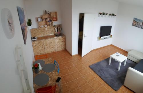 una pequeña sala de estar con mesa y TV. en Apartman Lena, en Osijek