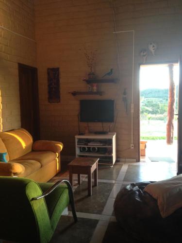 een woonkamer met een bank en een televisie bij Chácara Canto da Mata in Cavalcante