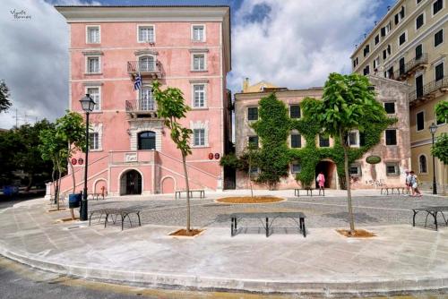 a courtyard with benches in front of a pink building at Carpe Diem Luxury Apartment No 1 in Corfu Town