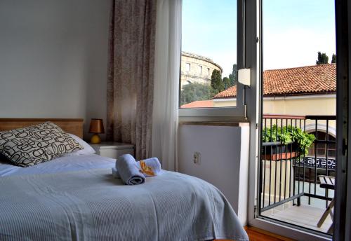 een slaapkamer met een bed en een groot raam bij Amphitheatre Apartments in Pula