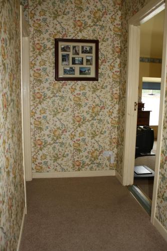 a hallway with a wall covered in floral wallpaper at Woodhill House in Ardara
