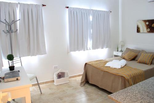 a white bedroom with a bed and a desk and window at Complejo Amarelo in Chajarí
