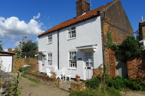 a white house with two white chairs in front of it at Weavers Cottage in Southwold