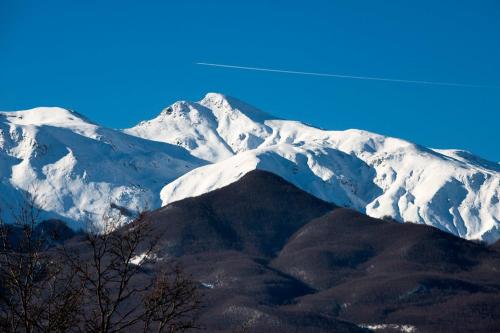 a snow covered mountain in the distance with a blue sky at B&B Le Peschiere in Montefiorino