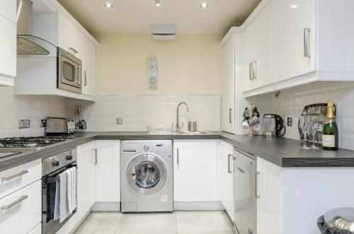 ベルファストにあるCentral City Apartment - Free Parkingのキッチン(白いキャビネット、洗濯機、乾燥機付)