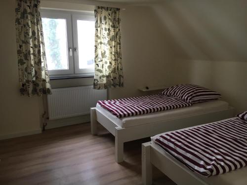 two beds in a room with a window at Huck’s Ferienhäuser in Borstel