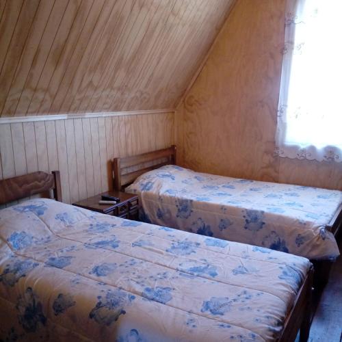 Duas camas num pequeno quarto com uma janela em Casa Lange em Valdivia