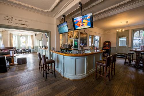 eine Bar in einem Restaurant mit Stühlen und einem TV in der Unterkunft The Milford Arms in Hounslow