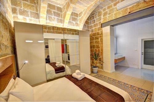 ein Schlafzimmer mit einem Bett und einem Spiegel in einem Zimmer in der Unterkunft Coral Apartment (Valletta) in Valletta