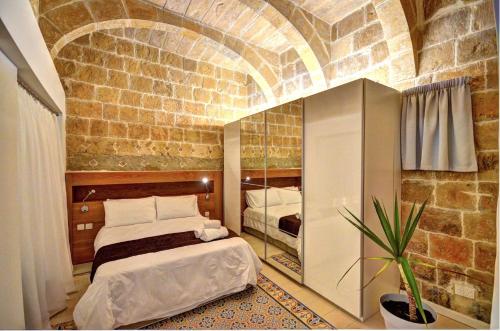 ein Schlafzimmer mit einem Bett und einer Ziegelwand in der Unterkunft Coral Apartment (Valletta) in Valletta