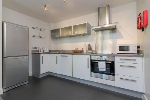 a kitchen with white cabinets and stainless steel appliances at iSTAY APARTMENTS at VIZION - Fully Equipped Modern Serviced Apartments with Balconies, Superfast Broadband, Free Allocated Parking Space, 24h Security, Rooftop Gardens, Located in Central MK in Milton Keynes