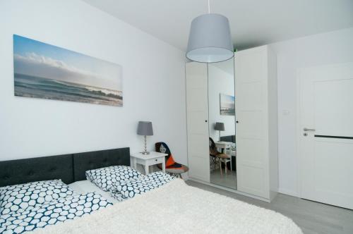 a white bedroom with a bed and a mirror at AquaBaltic in Kołobrzeg